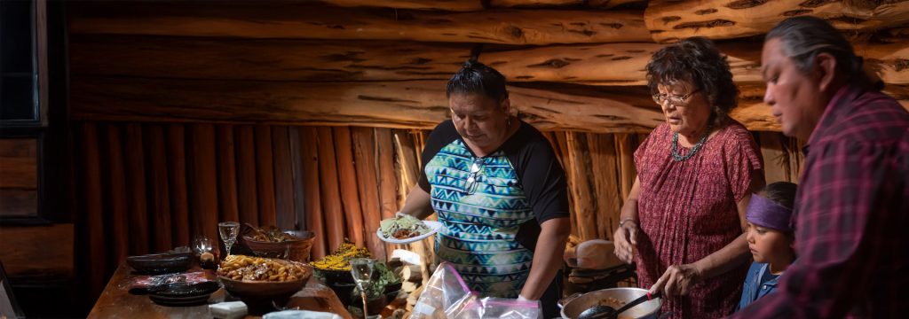 a family of mother sister husband and children around a table getting food