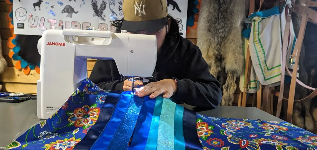 sitting behind a sewing machine, sewing a tradional quilt