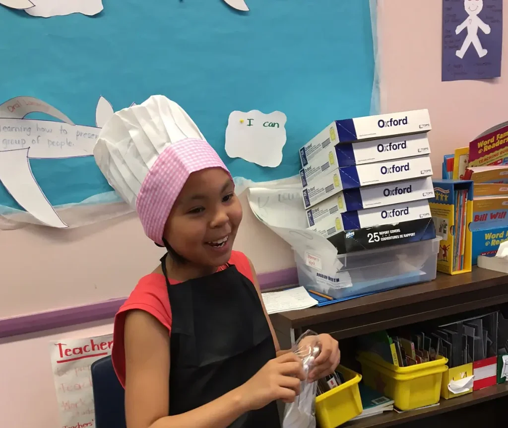 a girl dressed as a chef with a chef hat in a school setting