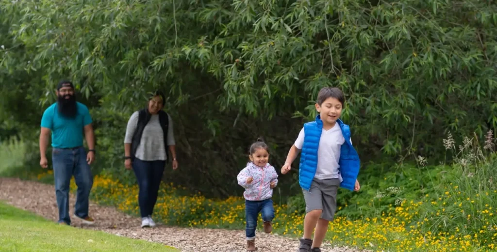 a mother and father walking on a path while a little boy and his younger sister are running ahead of them