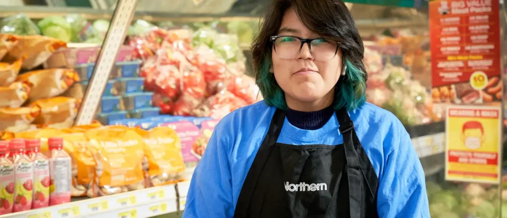 A young girl employee with glasses stands in front of the produce counter. Ask her anything about the produce.