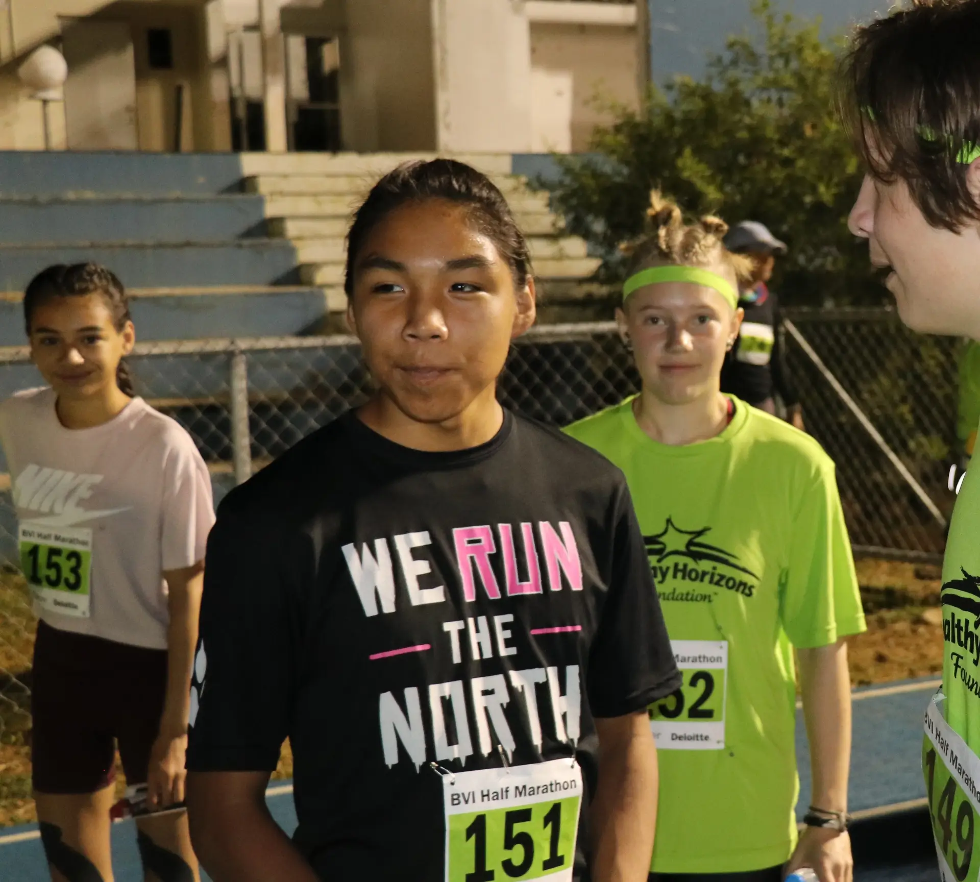 kids on a running track, one wearing a black shirt that reads "We Run the North" with a BVI marathon bib