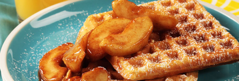 Waffles with apples in cinnamon sauce on a blue plate