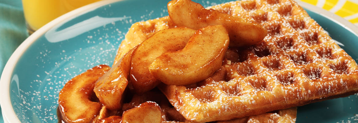 Waffles with apples in cinnamon sauce on a blue plate