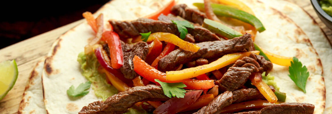 strips of peppers, steak onions on a tortilla