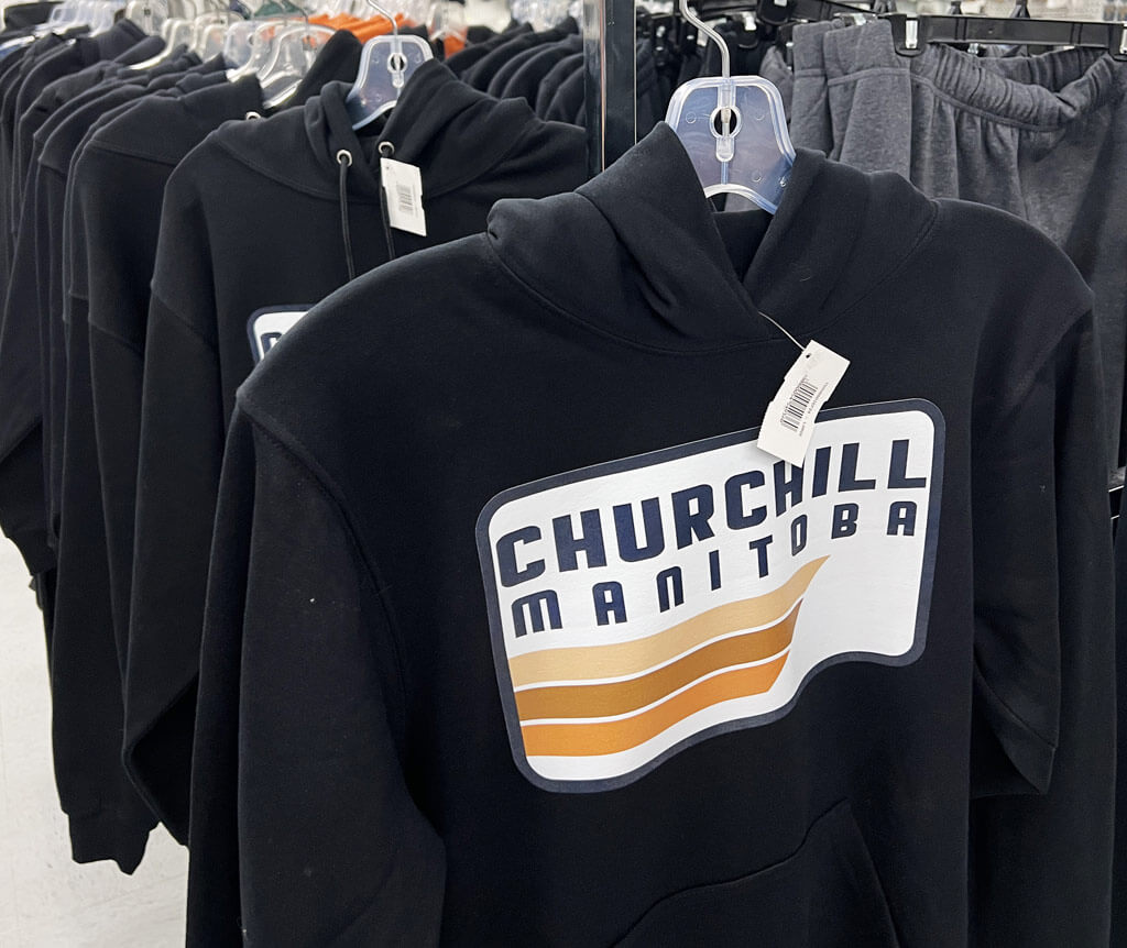 black hoodies hanging on a display rack, they have the tow Churchill Manitoba on the front