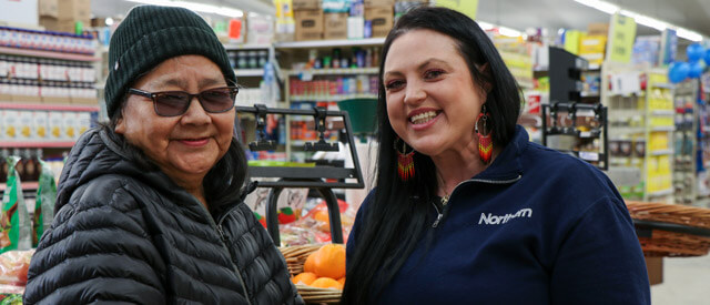 Two women, a elderly customer and a younger woman wearing a blue Northern shirt together
